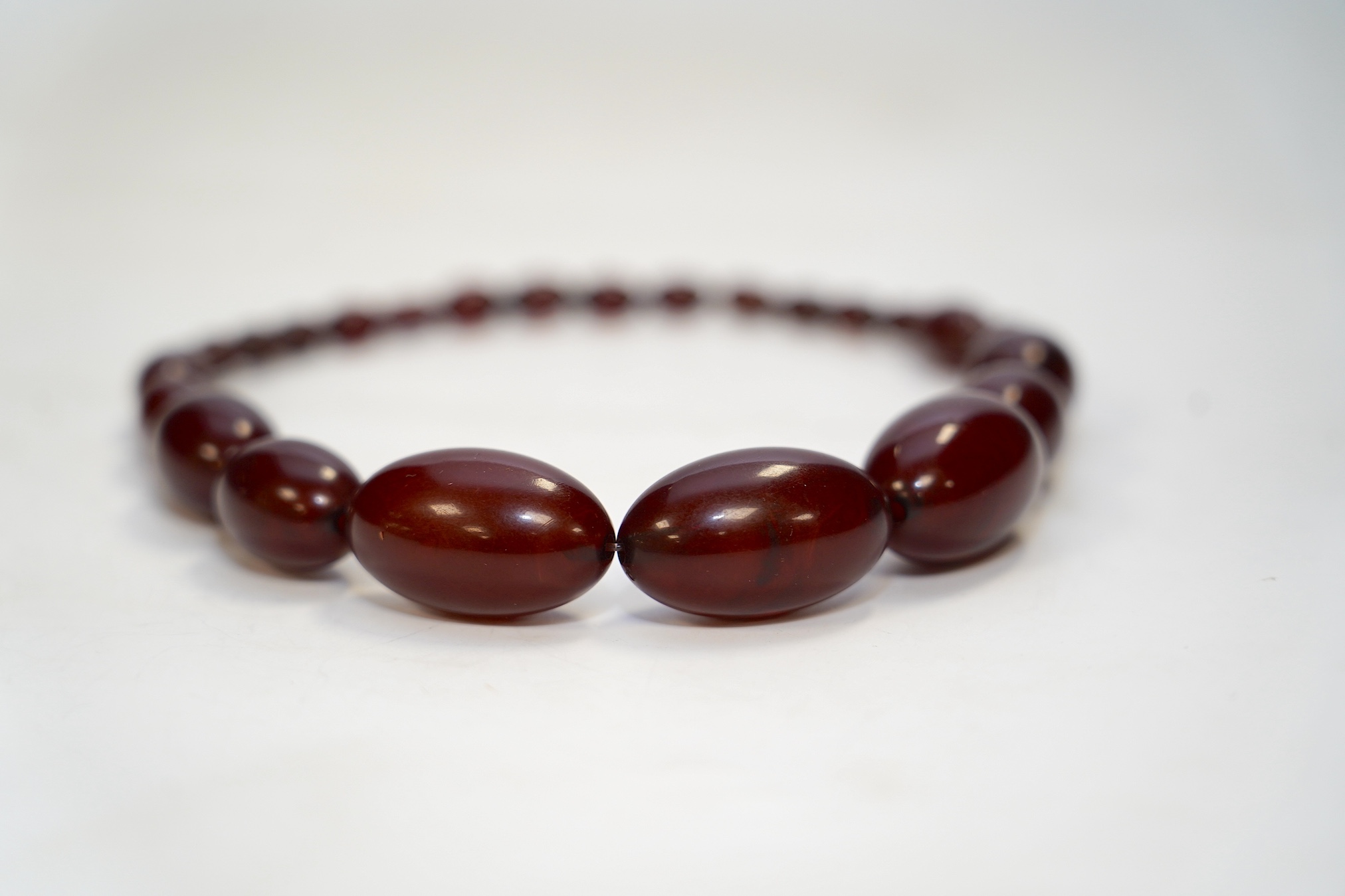 A single strand graduated simulated cherry amber bead necklace, 38cm, gross weight 65 grams. Condition - fair.